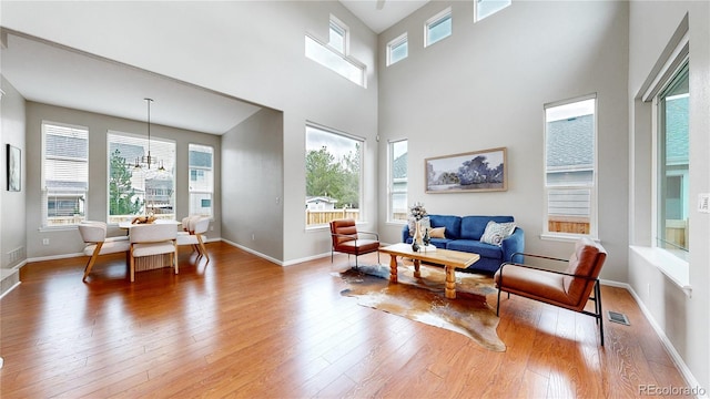 sitting room with baseboards, a notable chandelier, wood finished floors, and visible vents