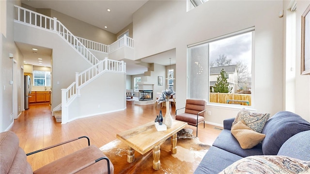 living area featuring stairway, a towering ceiling, baseboards, and wood finished floors