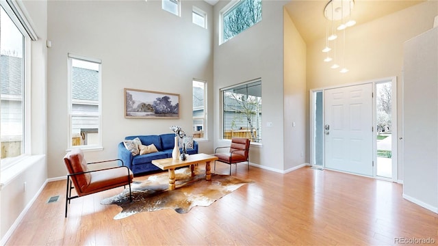 foyer entrance with wood finished floors, visible vents, a towering ceiling, and baseboards