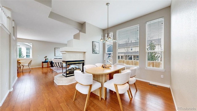 dining area featuring visible vents, a tile fireplace, baseboards, and light wood-style flooring