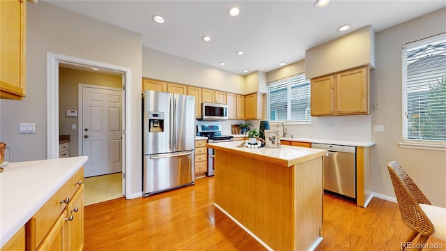 kitchen with light brown cabinets, a sink, light wood finished floors, light countertops, and appliances with stainless steel finishes