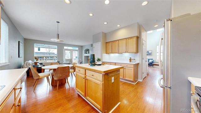 kitchen featuring light brown cabinets, open floor plan, light wood-style floors, light countertops, and appliances with stainless steel finishes