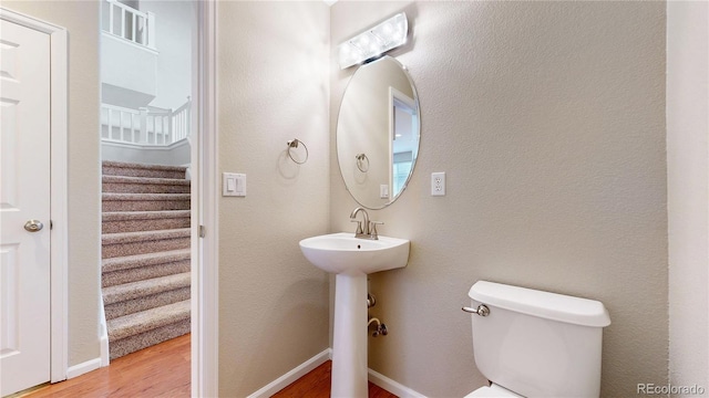 bathroom with wood finished floors, toilet, baseboards, and a sink