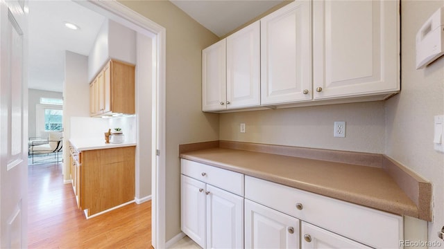 kitchen featuring light wood-type flooring, baseboards, light countertops, and white cabinets