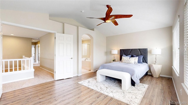 bedroom with arched walkways, lofted ceiling, a ceiling fan, wood finished floors, and connected bathroom