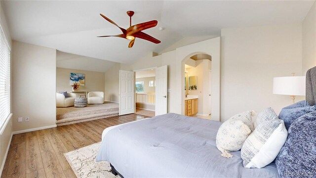 bedroom featuring vaulted ceiling, ceiling fan, arched walkways, light wood-style flooring, and baseboards