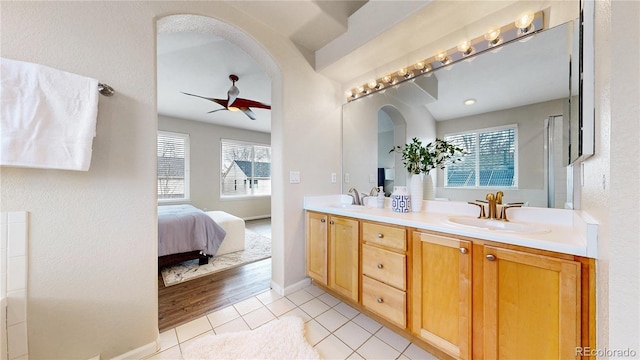 ensuite bathroom with tile patterned flooring, ceiling fan, a sink, and double vanity