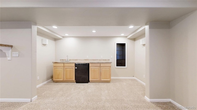 kitchen with refrigerator, baseboards, light brown cabinetry, and light colored carpet