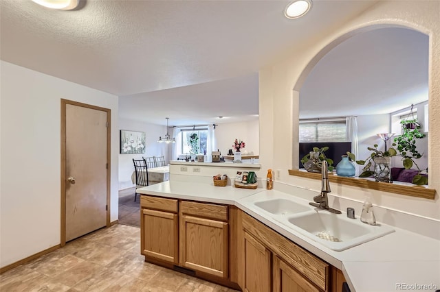 8900 Fox Dr Unit 1, Thornton, CO 80260 - kitchen with arched walkways, light countertops, a peninsula, and brown cabinets
