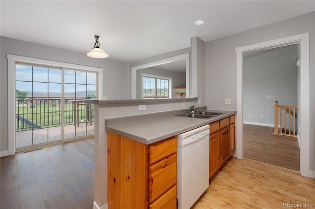 kitchen featuring sink, white dishwasher, light wood-type flooring, and pendant lighting