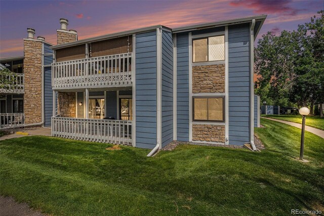8600 E Alameda Ave Unit 21-208, Denver, CO 80247 - back of property at dusk with stone siding, a lawn, and a balcony
