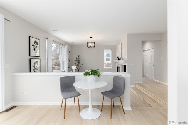 dining area featuring visible vents, plenty of natural light, light wood-style flooring, and baseboards