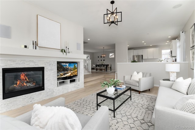 living area with a chandelier, light wood finished floors, a glass covered fireplace, and recessed lighting