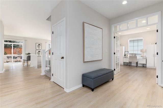 corridor with plenty of natural light, light wood-type flooring, stairs, and visible vents