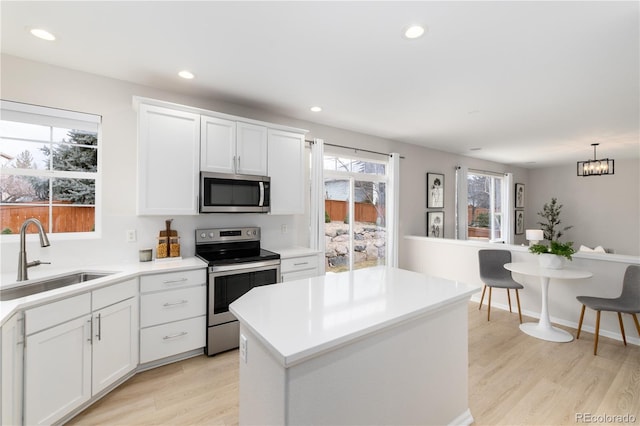 kitchen featuring stainless steel appliances, recessed lighting, light countertops, a sink, and light wood-type flooring