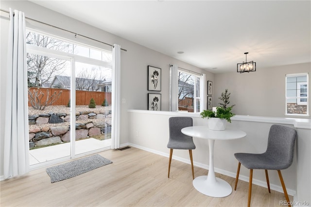 dining area with baseboards, wood finished floors, and a notable chandelier