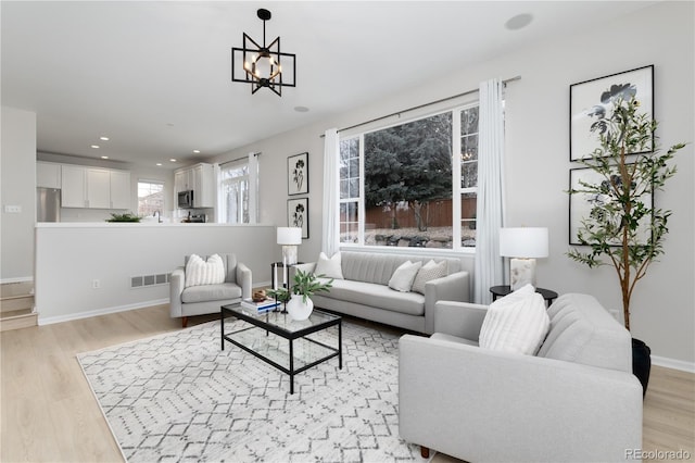 living area featuring light wood finished floors, recessed lighting, visible vents, an inviting chandelier, and baseboards