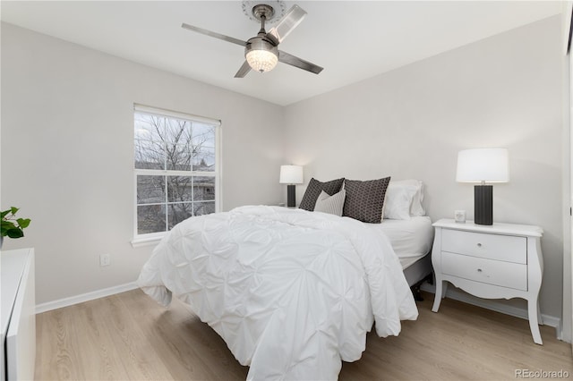 bedroom featuring light wood finished floors, a ceiling fan, and baseboards