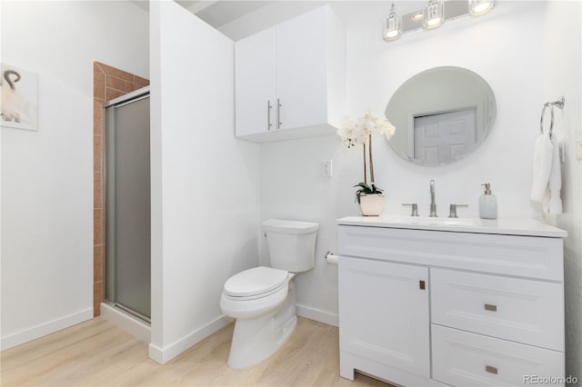 bathroom with baseboards, toilet, wood finished floors, vanity, and a shower stall