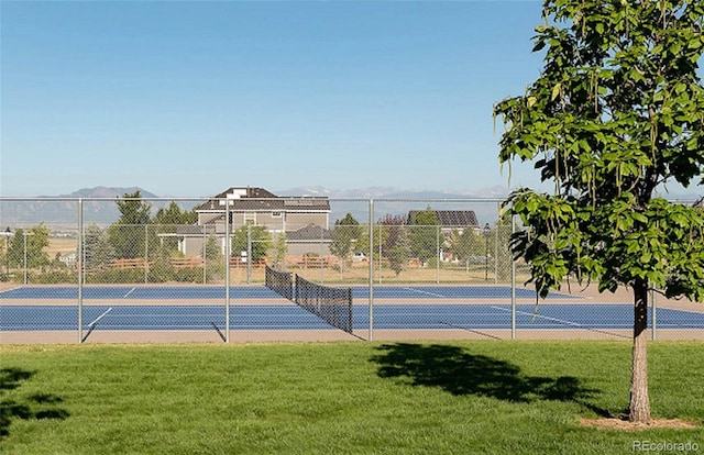 view of sport court with a mountain view, fence, and a lawn