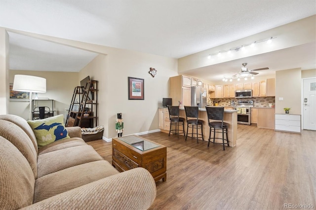 9625 E Center Ave Unit 5D, Denver, CO 80247 - living room with light wood finished floors, track lighting, a ceiling fan, and baseboards