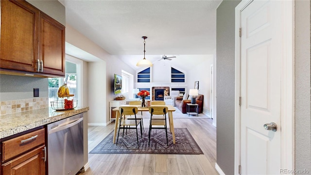 982 E 130th Cir, Thornton, CO 80241 - kitchen with dishwasher, a ceiling fan, a warm lit fireplace, light wood finished floors, and brown cabinets