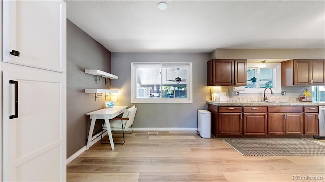 982 E 130th Cir, Thornton, CO 80241 - kitchen with light wood-type flooring, open shelves, stainless steel dishwasher, and light stone countertops