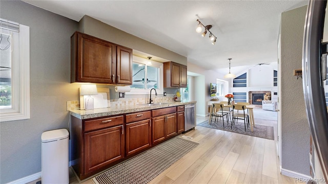 982 E 130th Cir, Thornton, CO 80241 - kitchen with light countertops, stainless steel dishwasher, a warm lit fireplace, light wood-type flooring, and a ceiling fan