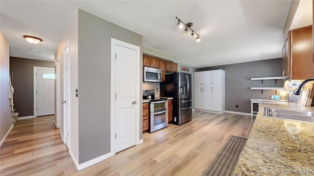 982 E 130th Cir, Thornton, CO 80241 - kitchen featuring stainless steel appliances, light wood finished floors, and brown cabinetry