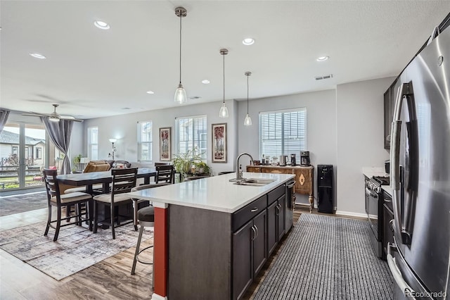 9679 Waco St, Commerce City, CO 80022 - kitchen with appliances with stainless steel finishes, open floor plan, light countertops, a center island with sink, and dark wood finished floors