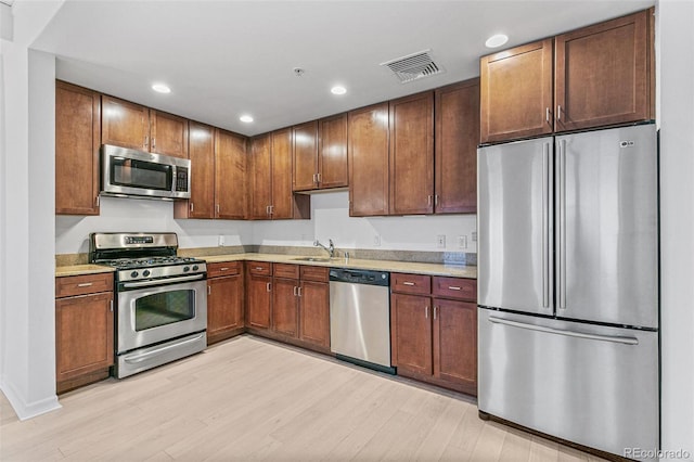 kitchen with sink, light hardwood / wood-style floors, and appliances with stainless steel finishes