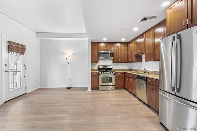 kitchen featuring stainless steel appliances, sink, and light hardwood / wood-style flooring