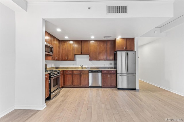 kitchen featuring appliances with stainless steel finishes, sink, and light wood-type flooring