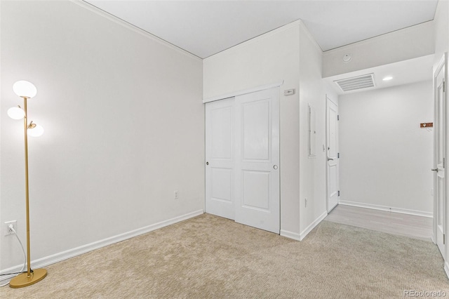 unfurnished bedroom featuring light colored carpet and a closet