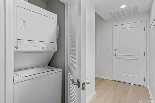 laundry area featuring light wood-type flooring and stacked washer / dryer