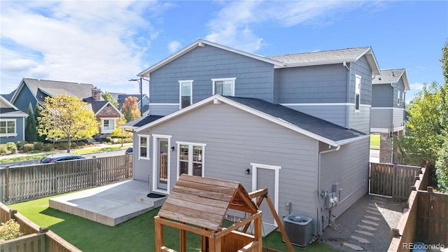 rear view of property with a patio, central AC, and a lawn