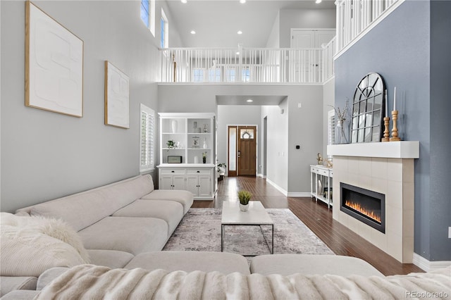 living room featuring a high ceiling, a tile fireplace, and dark hardwood / wood-style floors