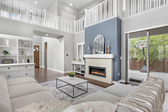 living room with a fireplace, hardwood / wood-style flooring, and a towering ceiling