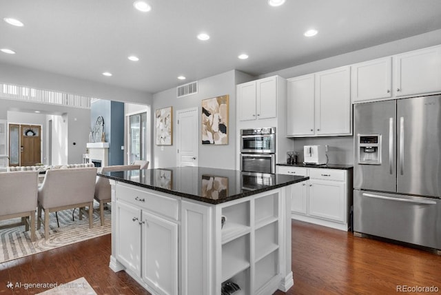 kitchen featuring stainless steel appliances, dark stone counters, a center island, white cabinets, and dark hardwood / wood-style flooring