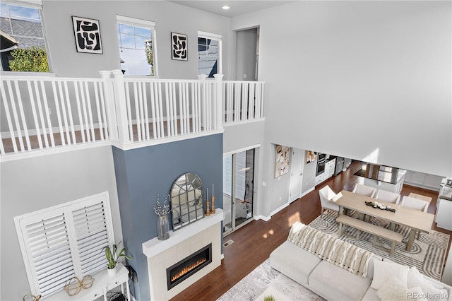 living room with a tile fireplace, dark wood-type flooring, and a high ceiling