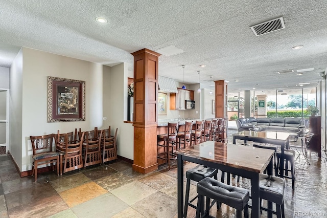 2225 Buchtel Blvd Unit 105, Denver, CO 80210 - dining room with decorative columns, a textured ceiling, light stone finish flooring, and floor to ceiling windows