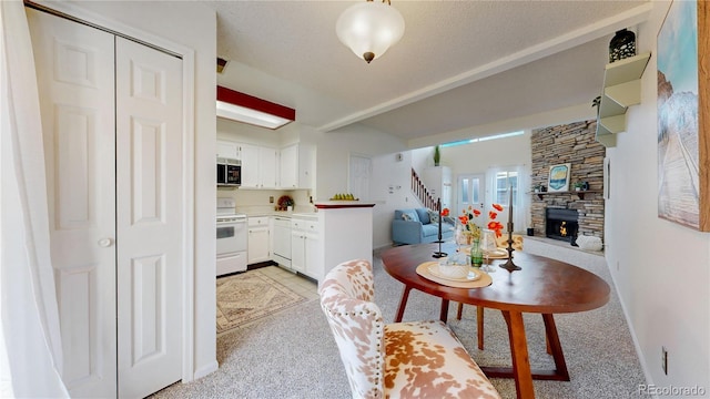 kitchen with a stone fireplace, pendant lighting, a textured ceiling, white appliances, and white cabinets