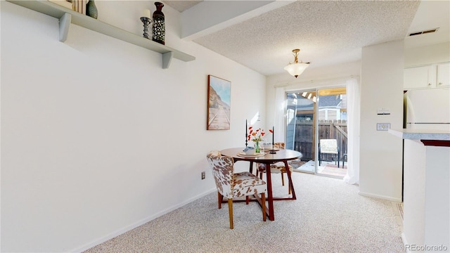 carpeted dining room featuring a textured ceiling