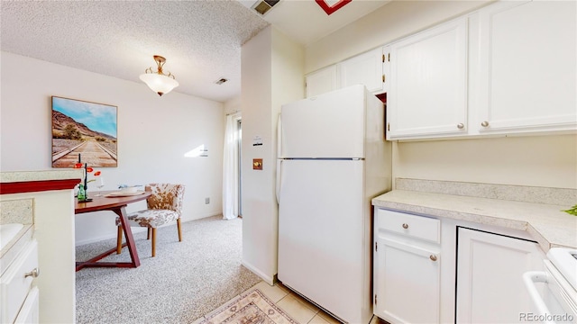 kitchen with stove, white fridge, a textured ceiling, light carpet, and white cabinets