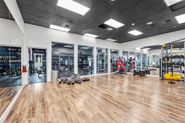 workout area featuring a drop ceiling, wood finished floors, visible vents, and a high ceiling