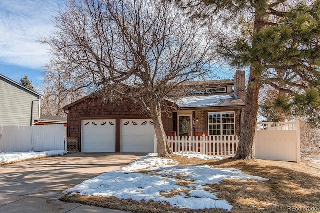 view of front of house featuring an attached garage, a fenced front yard, a chimney, and concrete driveway