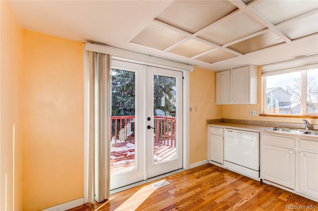 kitchen with french doors, light wood finished floors, white cabinets, white dishwasher, and a sink