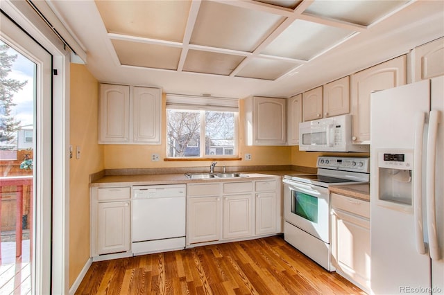 kitchen with white appliances, light wood finished floors, and a sink