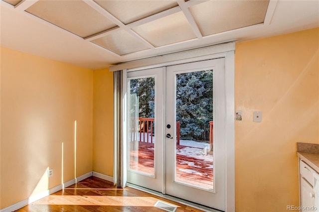 doorway to outside with coffered ceiling, wood finished floors, visible vents, baseboards, and french doors