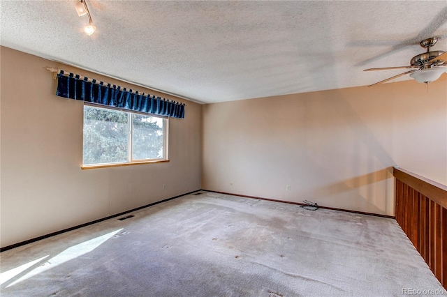 carpeted spare room featuring baseboards, visible vents, and a textured ceiling